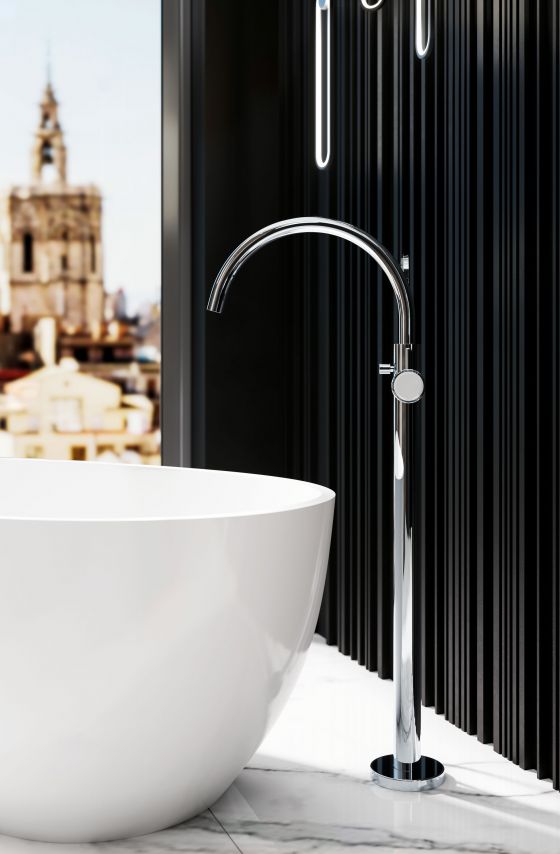 Freistehende Wannenarmatur aus der Valencia-Serie in Chrom zusammen mit einer freistehenden Badewanne in Weiß vor schwarzem Hintergrund.